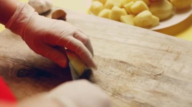 Videocu kadın şefin elleri taze patates sebzeleri soyarken mutfaktaki tahta kesme tahtasının altına keskin bir sopa saplıyor. Yiyecek kazıntıları, sıfır yeşil organik atık ve sağlıklı beslenme..