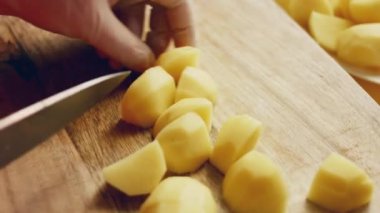 Videocu kadın şefin elleri taze patates sebzeleri soyarken mutfaktaki tahta kesme tahtasının altına keskin bir sopa saplıyor. Yiyecek kazıntıları, sıfır yeşil organik atık ve sağlıklı beslenme..
