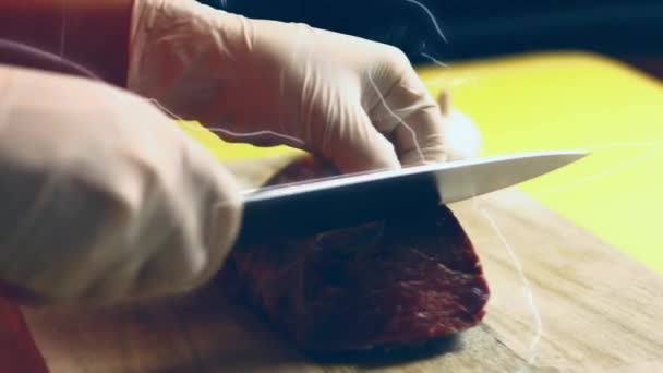 シェフは生肉をきれいにし 鋭いナイフで生牛のヒレ肉から結合組織と表面膜を切断します — ストック動画