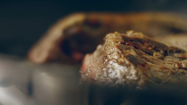 他の肉やソーセージに囲まれた炎のグリルでローズマリーでブラッシュアップジューシーなステーキ肉の牛肉を調理 スローモーション — ストック動画