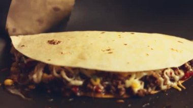 Kızartma tavasında taze sarılmış tavuk quesadilla kızartıyorum. Örtüyü çıkarıyorum. Meksika usulü quesadillas yapma süreci