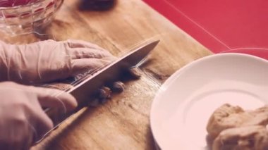 Aşçı elleri yakın plan, kadın çiğ tavuk göğsünü tahta tahtayla kesiyor..