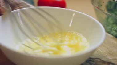 Sabah omleti ya da çırpılmış yumurta için çırpılmış yumurtaları metal kâsede çırpın. Fırında hamur hazırlamak için yumurta çırpıyorum. Kahvaltı hazırlama kavramı.