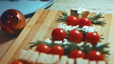 Peynir ve domates düzlüğü. Noel ağacı şeklinde dizilmiş peynir, domates ve rozmarin dilimleri. Noel tatili için yemek. Döndürme. Yavaş çekim.