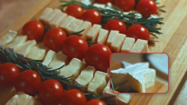 Peynir ve domates düzlüğü. Noel ağacı şeklinde dizilmiş peynir, domates ve rozmarin dilimleri. Noel tatili için yemek. Döndürme. Yavaş çekim.
