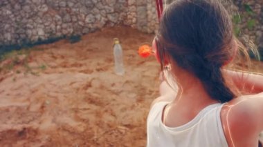 Childrens hands hold a bow and arrow and shoot at target on door.