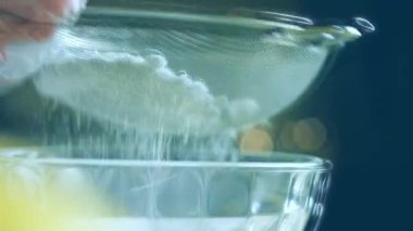 Paslanmaz çelik elek aracılığıyla pudra şekeri veriyorum. Ev yapımı zencefilli kurabiye için krema hazırlıyorum..