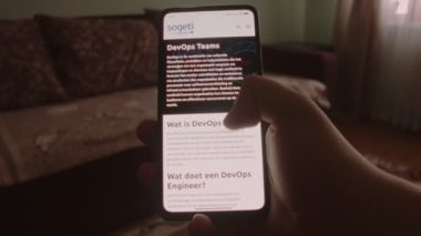 DevOps Takımları. Cep telefonu ekranında DevOps ekipleri hakkında bilgi aranıyor