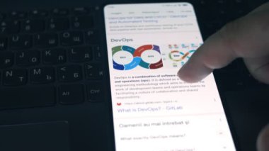 Devop 'lar. Cep telefonu ekranında DevOps hakkında bilgi okunuyor