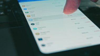 Yatırımcı cep telefonu ekranında Bitcoin, Ethereum ve diğer altsikke kripto para fiyat indeksini kontrol ediyor. Hologram etkisi