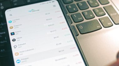 Yatırımcı cep telefonu ekranında Bitcoin, Ethereum ve diğer altsikke kripto para fiyat indeksini kontrol ediyor. Hologram etkisi
