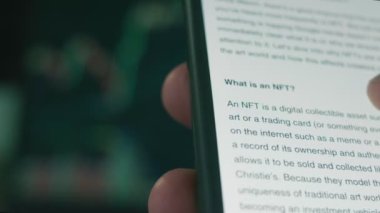 Cep telefonu ekranında NFT hakkında bilgi. Finansal olmayan Jeton NFT, sanat, video klipler, müzik ve daha fazlası gibi gerçek eşyaların mülkiyetini temsil eden eşsiz bir dijital varlıktır. Hologram etkisi