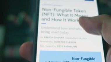 Cep telefonu ekranında NFT hakkında bilgi. Finansal olmayan Jeton NFT, sanat, video klipler, müzik ve daha fazlası gibi gerçek eşyaların mülkiyetini temsil eden eşsiz bir dijital varlıktır. Hologram etkisi