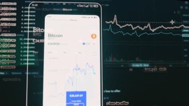 Cep telefonu ve bilgisayar ekranındaki şifreli veriler. Kripto para birimi konsepti. Piyasa fiyatlandırması. Bitcoin 'in finansal endeksleri zaman içinde borsa duvarında aşağı yukarı değişiyor. Hologram etkisi