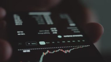 Tüccar yatırımcı analisti cep telefonu uygulaması kullanıyor. Finansal borsa analizleri. Grafik ticareti verilerini analiz eden yatırımcı