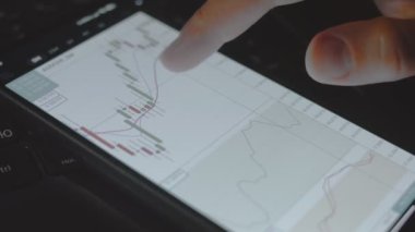 Tüccar yatırımcı analisti cep telefonu uygulaması kullanıyor. Finansal borsa analizleri. Yatırımcı histogram ticaret verilerini analiz ediyor. Makro görünüm
