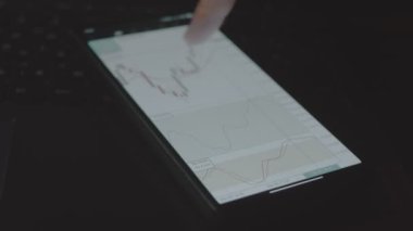 Tüccar yatırımcı analisti cep telefonu uygulaması kullanıyor. Finansal borsa analizleri. Yatırımcı histogram ticaret verilerini analiz ediyor. Makro görünüm