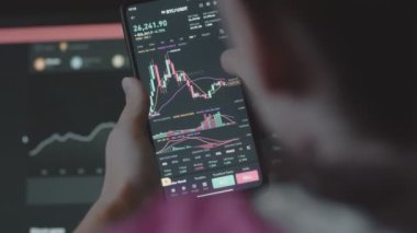 Ticari yatırımcı analisti cep telefonu uygulaması ve bilgisayar kullanıyor. Kripto para birimi finansal borsası analizleri. Bitcoin fiyat endeksinin histogramını analiz eden yatırımcı