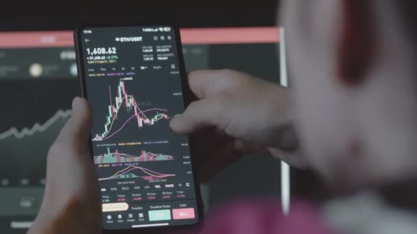 携帯電話アプリとコンピュータを使用してトレーダー投資家アナリスト 仮想通貨金融株式市場のための分析 イーサリアム価格指数のヒストグラムを分析する投資家 — ストック動画