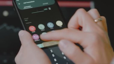 Akıllı para yönetimi. Bütçeyi izlemek için teknolojiyi kullanmak. Hesaplarını yapmak için cep telefonu kullanan biri. Eğitim kategorisine yeni harcamalar ekleniyor