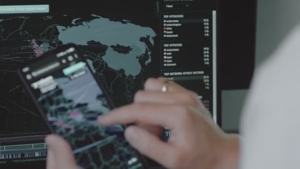 携帯電話とコンピュータの画面上の世界地図による世界的なサイバー攻撃 サイバー攻撃の下でのネットワーク通信 オンラインウイルスの世界的な伝播のための統計 — ストック動画