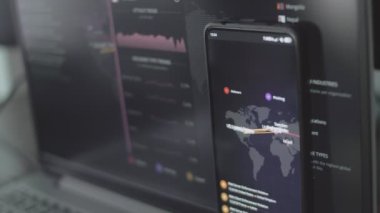 Cep telefonu ve bilgisayar ekranında dünya haritası olan küresel siber saldırı. İnternet ağı iletişimi siber saldırı altında. Çevrimiçi dünya çapında virüs yayılımı