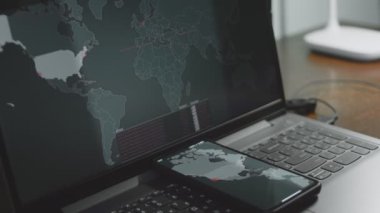 Cep telefonu ve bilgisayar ekranında dünya haritasıyla küresel siber saldırı. İnternet ağı iletişimi siber saldırı altında. Dünya çapında virüs yayılımı çevrimiçi. Yakın çekim.