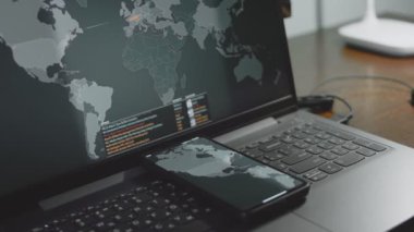 Cep telefonu ve bilgisayar ekranında dünya haritasıyla küresel siber saldırı. İnternet ağı iletişimi siber saldırı altında. Dünya çapında virüs yayılımı çevrimiçi. Yakın çekim.