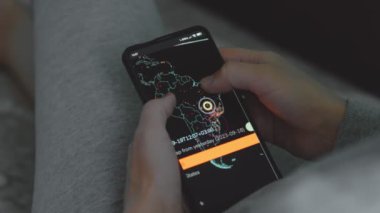 Cep telefonu ekranında dünya haritasıyla küresel siber saldırı, haritada Güney Amerika. İnternet ağı iletişimi siber saldırı altında. Dünya çapında virüs yayılımı çevrimiçi. Yakın çekim.