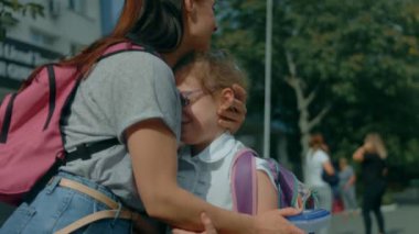 Sevgi dolu aile. Şefkatli anne okuldan kızıyla tanışır. Anne okuldan sonra kızını sırt çantasıyla kucaklıyor. Okula geri dön.