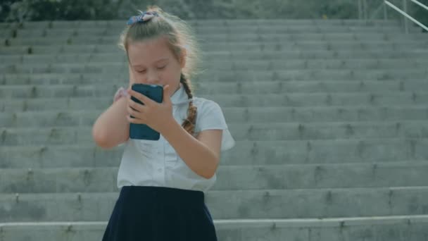 Mosolygó Aranyos Iskolás Lány Játszik Okostelefonnal Vidám Lány Megérinti Mobiltelefon — Stock videók