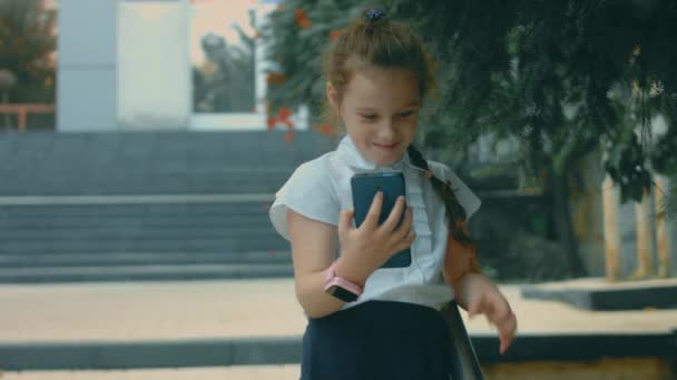 Lächelndes Süßes Schulmädchen Das Mit Dem Smartphone Spielt Fröhliche Jährige — Stockvideo