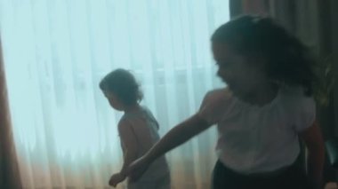 Saçları örgülü, kıvırcık kreş kızı gülümseyen ve evlerinde koşuşturan mutlu küçük kız. Evde eğleniyorum..