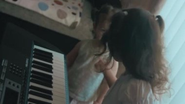 Kafkasyalı genç müzisyen kız eğlenceli aktiviteler yapıyor evde müzik eğitimi alanında piyano dersi veriyor. Küçük kız kardeşi onun oyununu dinleyerek eğleniyor.