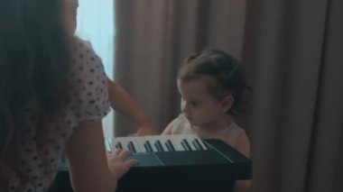 Kafkasyalı genç müzisyen kız eğlenceli aktiviteler yapıyor evde müzik eğitimi alanında piyano dersi veriyor. Küçük kız kardeş de oynamaya çalışıyor. Kızlar eğlenin.