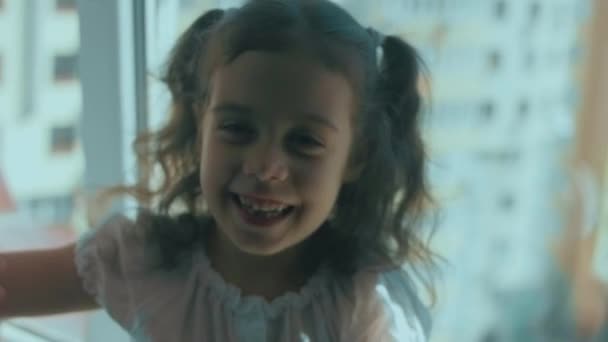 Όμορφη Σγουρή Κοπέλα Που Κάθεται Στο Περβάζι Χαμογελώντας Και Παίζοντας — Αρχείο Βίντεο
