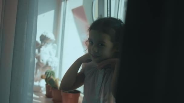 漂亮的卷曲女孩坐在窗台上 微笑着坐在家里 甩着头发 在家里玩得开心 — 图库视频影像