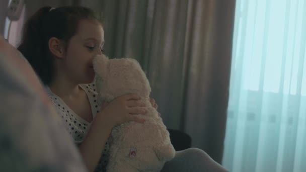 可爱快乐的女学生抱着玩具熊玩耍 很高兴抱着她最喜欢的玩具朋友 漂亮的孩子在家里 坐在沙发上 — 图库视频影像