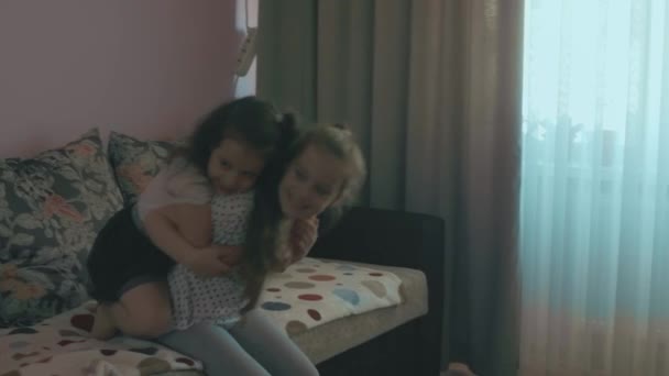 两个可爱的姐姐在沙发上玩耍 女学生和学龄前姐姐在家里玩得很开心 — 图库视频影像