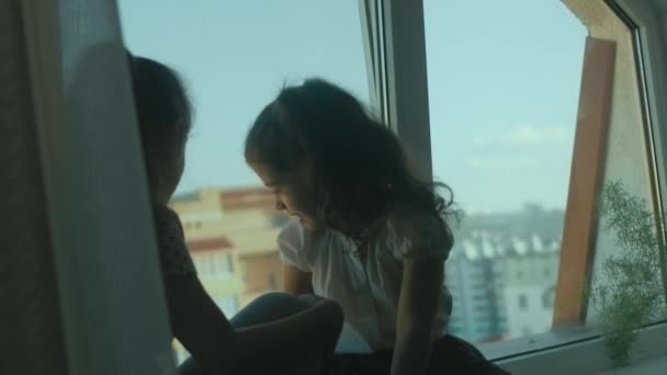 两个姐姐都在玩得很开心 她们说着话 看着窗外 坐在靠近大窗户的窗台上 — 图库视频影像