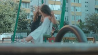 Güneşli bir yaz gününde parkta salıncakta sallanan iki mutlu kız. Kız kardeşimle keyifli bir gün geçiriyorum.