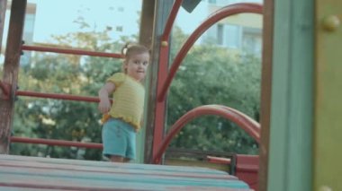 Küçük bir evde, çocuk parkında mutlu gülümseyen küçük kız, sonra kayıyor
