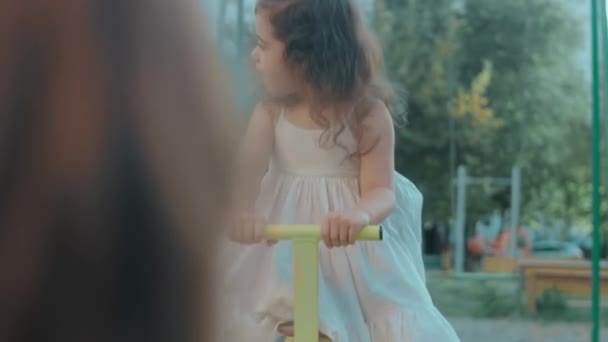 Χαρούμενα Μικρά Καυκάσια Κορίτσια Κάθονται Μια Μεταλλική Κούνια Στην Παιδική — Αρχείο Βίντεο