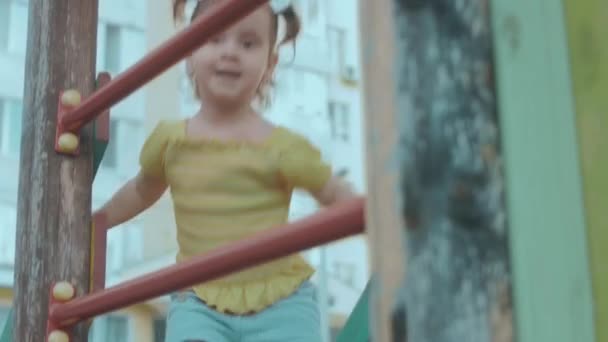 在操场上的小房子里快乐地微笑着蹒跚学步的小女孩 — 图库视频影像