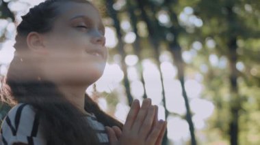 Güzel kıvırcık kız parkta Tanrı 'ya dua etmekten mutlu. Küçük çocuk büyük inanç