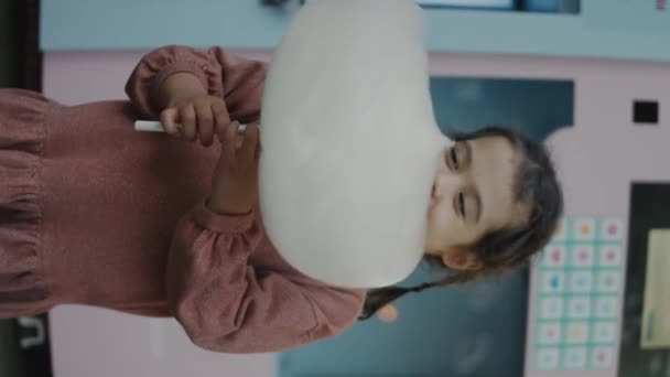 Pionowe Ujęcie Szczęśliwej Dziewczynki Delektującej Się Watą Cukrową Bardzo Podekscytowana — Wideo stockowe
