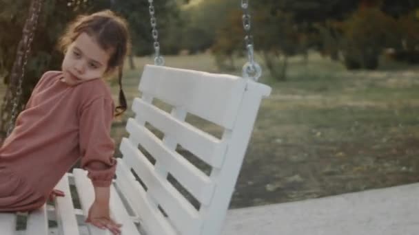 Little Girl Having Fun White Swing Quiet Tree Lined Park — Stock Video