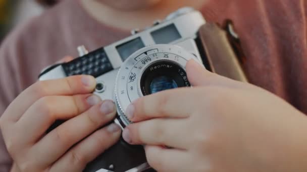 かわいい女の子は レトロカメラで自然の最初の写真を撮ります 子供の頃の写真撮影の第一歩を踏み出しました カメラレンズを設定する小さな手のクローズアップ — ストック動画