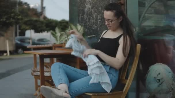 カフェで屋外に座ってコーヒーを待っている若い女性 リラクゼーション 気分の良い都市ライフスタイルのコンセプト — ストック動画