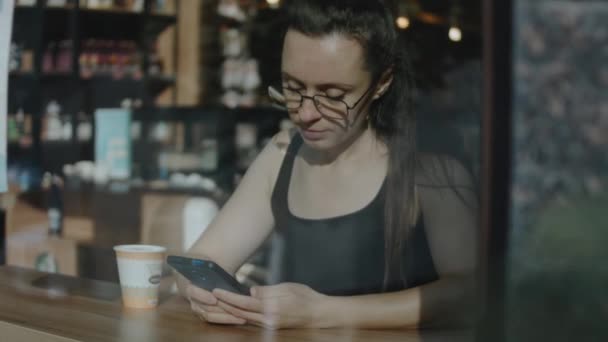 携帯電話を持っている女性の近くに コーヒー休憩中に携帯電話でビデオを見る 外からの眺め スローモーション — ストック動画